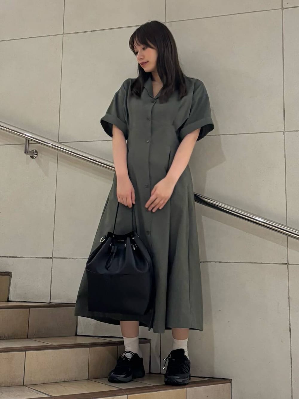 ブラック系のショルダーバッグ、ブラック系のスニーカー、グリーン系のワンピースを着用したレディースの夏コーディネートの2枚目の写真