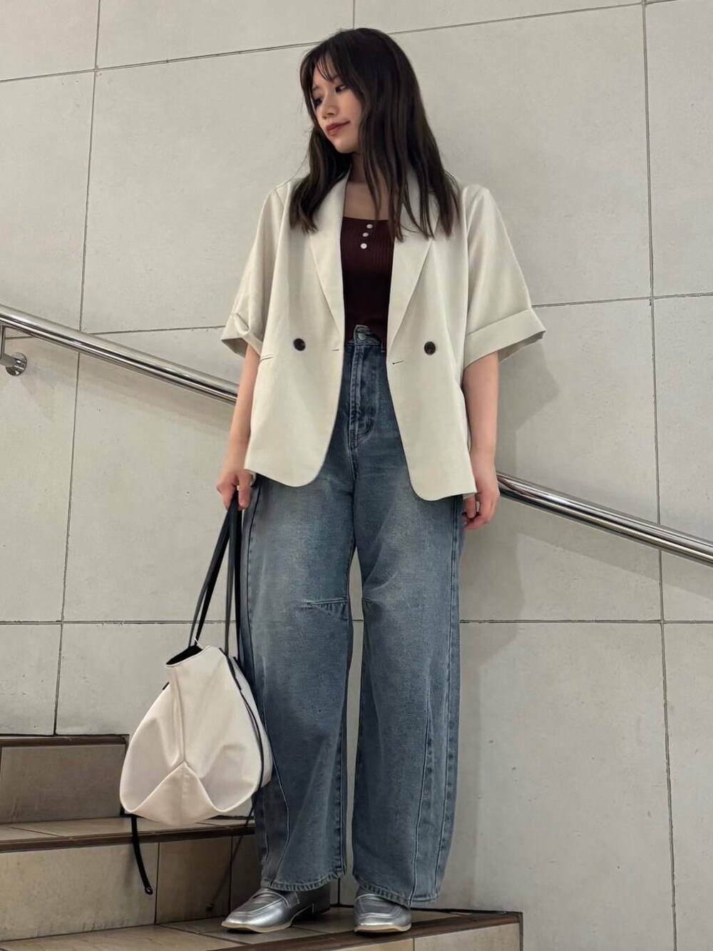 シルバー系のローファー、ブルー系のデニムパンツ、ベージュ系のトートバッグを着用したレディースの夏コーディネートの2枚目の写真
