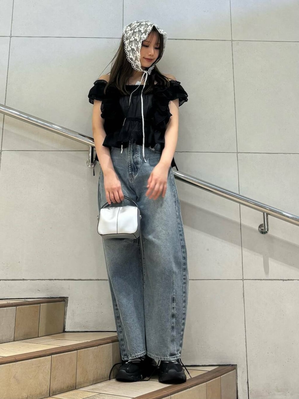 ブラック系のスニーカー、ホワイト系のキャミソール、ブルー系のデニムパンツを着用したレディースの春コーディネートの4枚目の写真