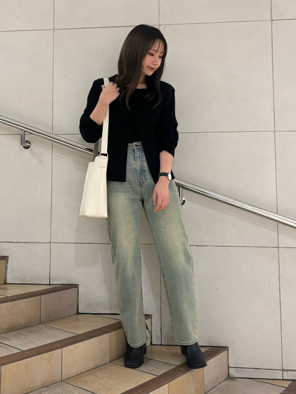 ベージュ系のショルダーバッグ、ブルー系のデニムパンツ、ブラック系のニット/セーターを着用したレディースの冬コーディネートの2枚目の写真
