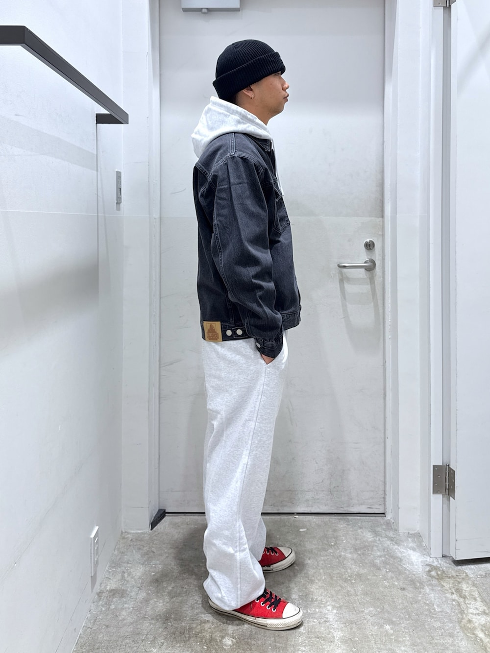 ブラック系のデニムジャケット、グレー系のパーカー、グレー系のスウェットパンツを着用したメンズの秋コーディネートの4枚目の写真