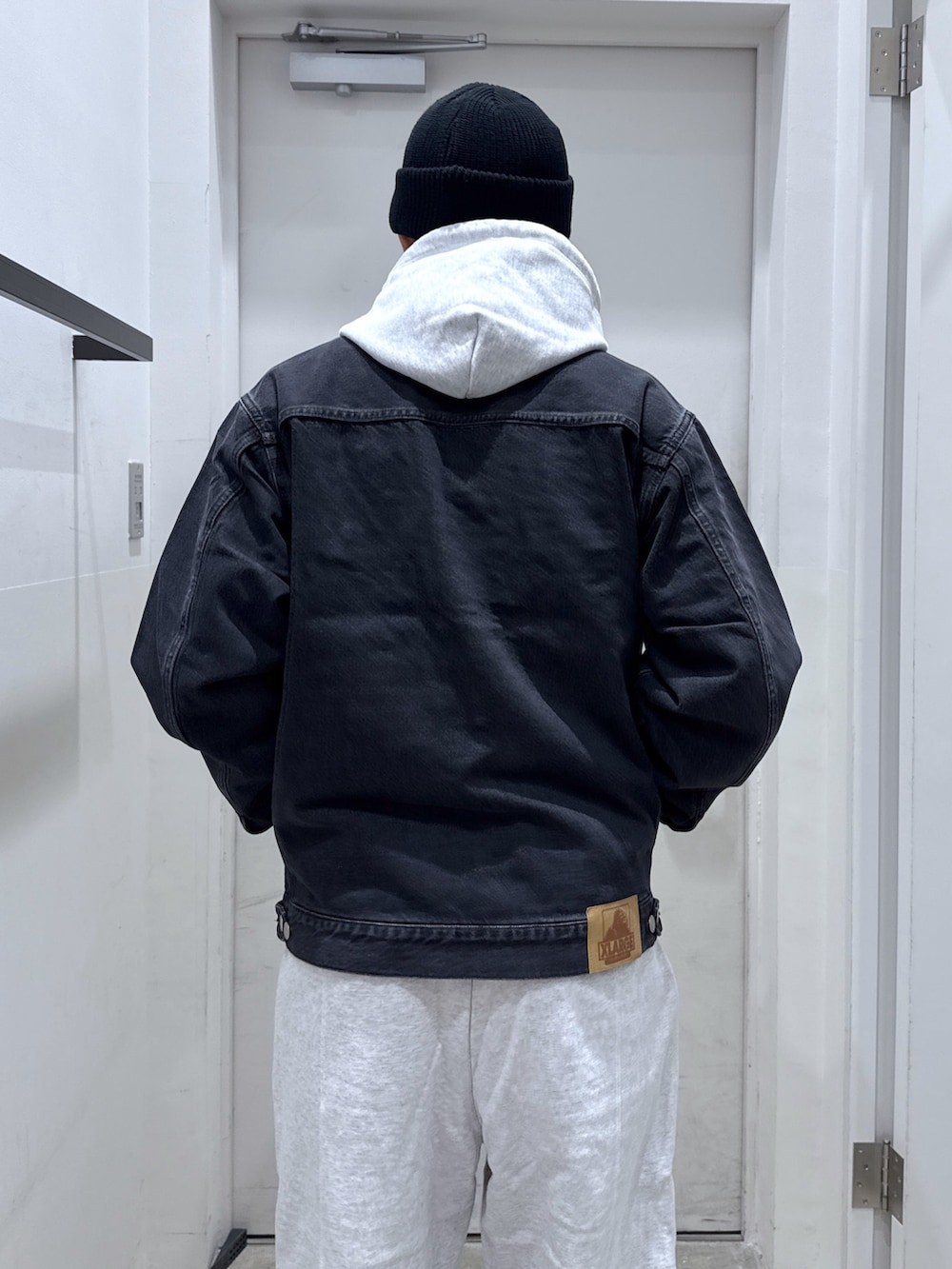 ブラック系のデニムジャケット、グレー系のパーカー、グレー系のスウェットパンツを着用したメンズの秋コーディネートの6枚目の写真