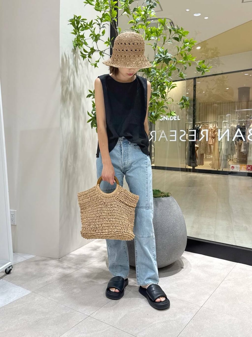 ベージュ系のトートバッグ、ブラック系のサンダル、ブラック系のセットアップを着用したレディースの夏コーディネートの4枚目の写真