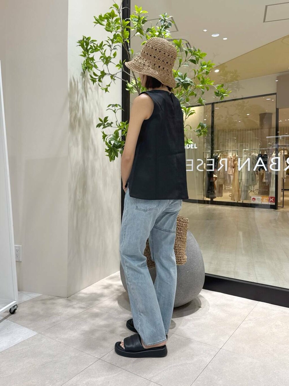 ベージュ系のトートバッグ、ブラック系のサンダル、ブラック系のセットアップを着用したレディースの夏コーディネートの2枚目の写真