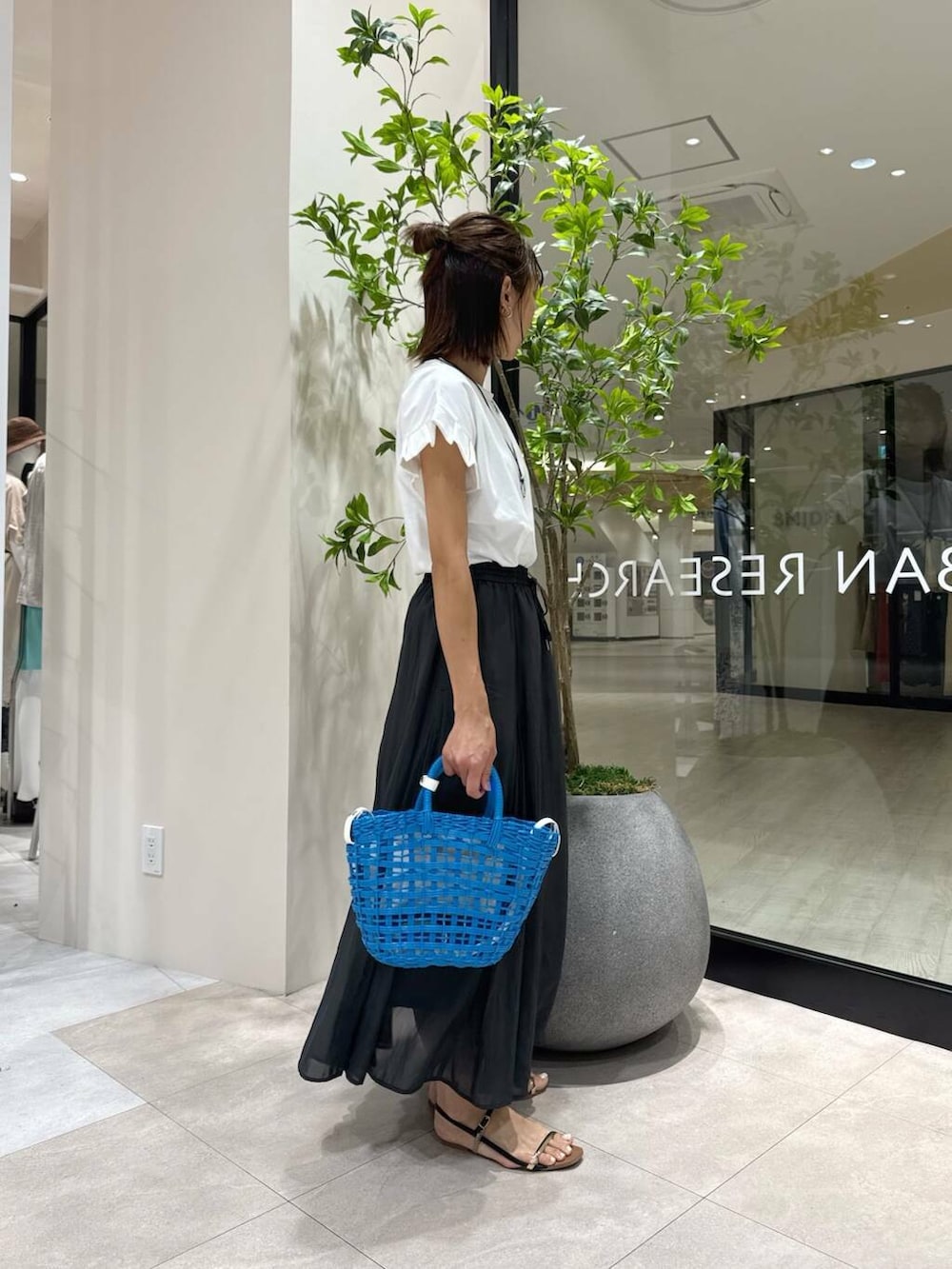 ブラック系のサンダル、ブルー系のかごバッグ、ブラック系のスカートを着用したレディースの夏コーディネートの4枚目の写真