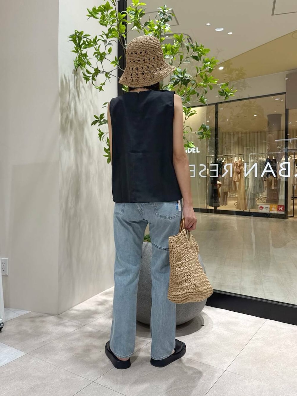 ベージュ系のトートバッグ、ブラック系のサンダル、ブラック系のセットアップを着用したレディースの夏コーディネートの3枚目の写真