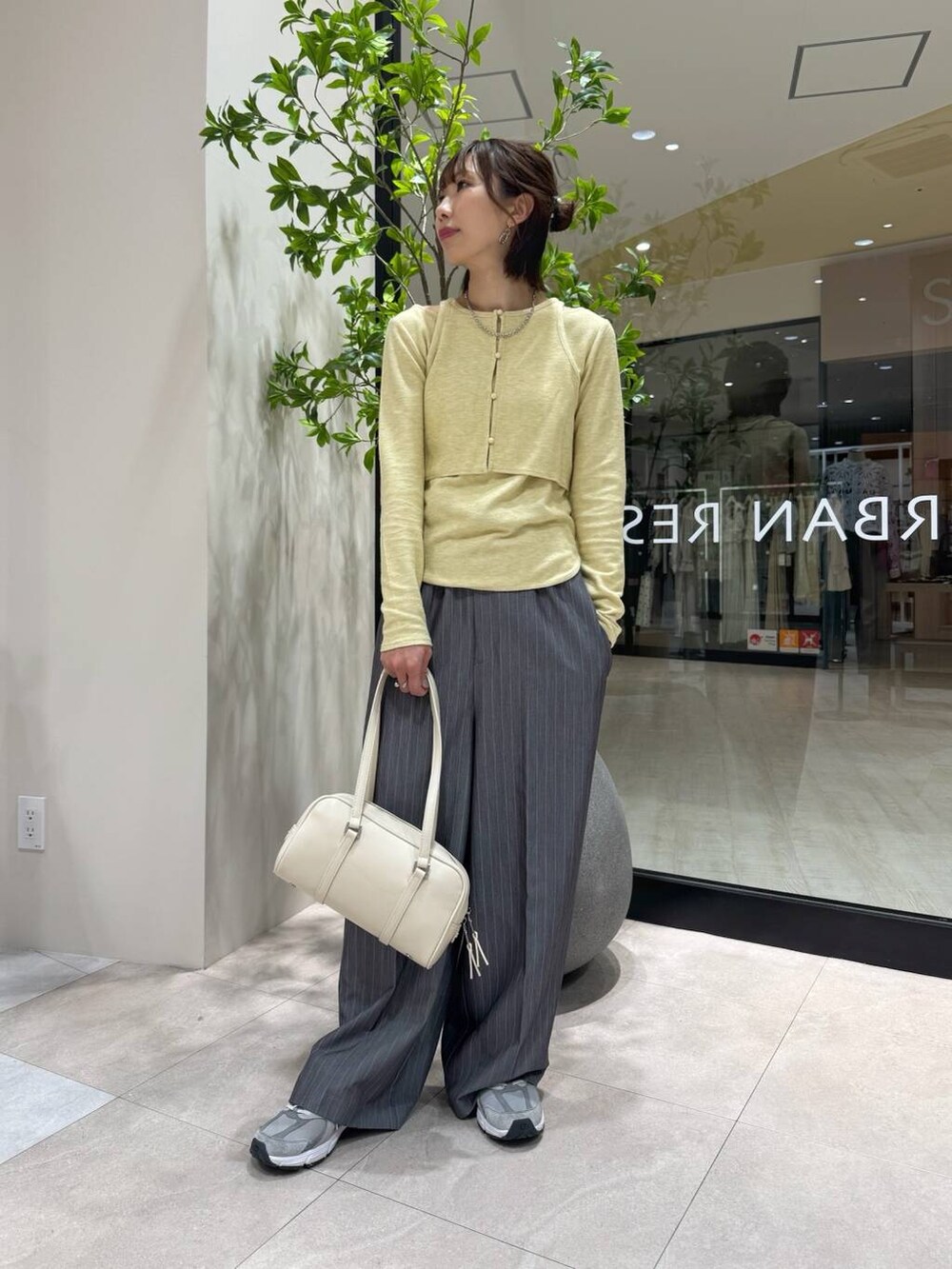 グレー系のサロペット/オーバーオール、ホワイト系のボストンバッグ、イエロー系のTシャツ/カットソーを着用したレディースの春コーディネートの4枚目の写真
