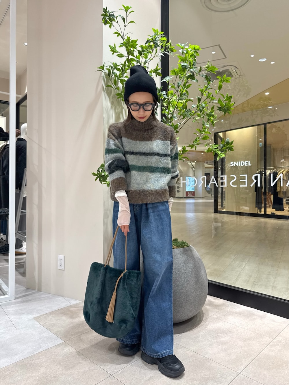 ブラウン系のニット/セーター、ホワイト系のTシャツ/カットソー、グリーン系のトートバッグを着用したレディースの秋コーディネートの4枚目の写真