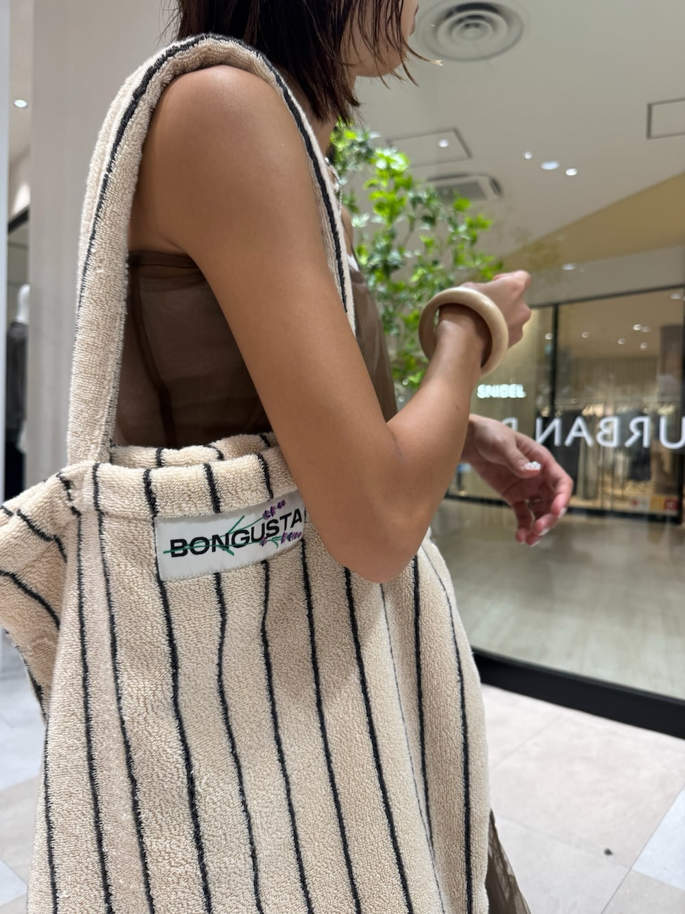 ベージュ系のキャミソール、ブラウン系のワンピース、ブルー系のデニムパンツを着用したレディースの秋コーディネートの4枚目の写真