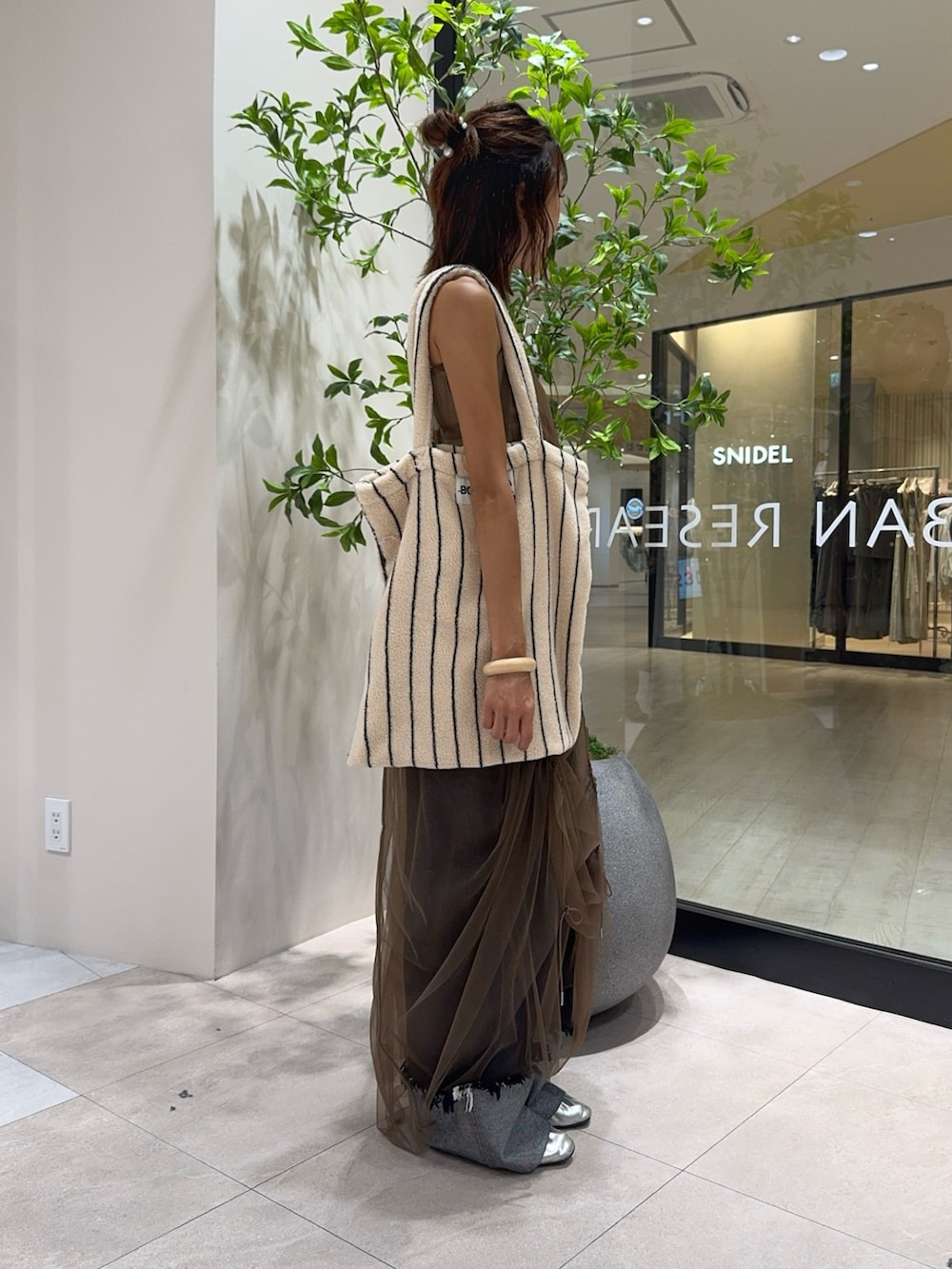 ベージュ系のキャミソール、ブラウン系のワンピース、ブルー系のデニムパンツを着用したレディースの秋コーディネートの3枚目の写真