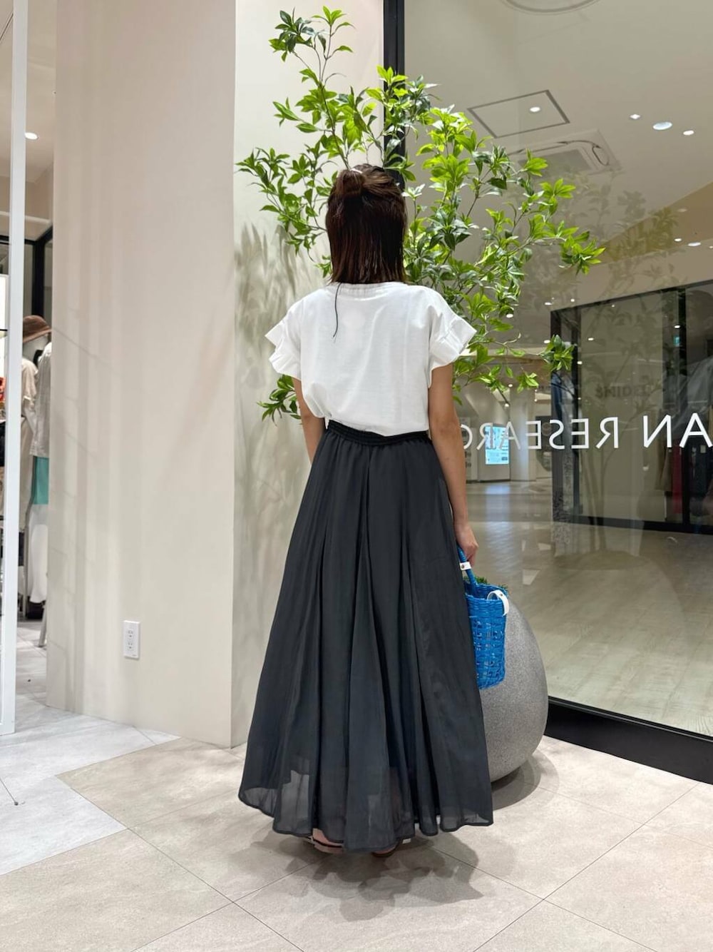 ブラック系のサンダル、ブルー系のかごバッグ、ブラック系のスカートを着用したレディースの夏コーディネートの3枚目の写真