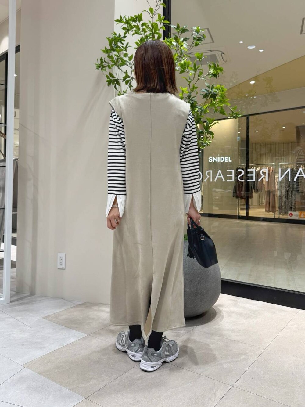 ブラック系のショルダーバッグ、ホワイト系のTシャツ/カットソー、グレー系のスニーカーを着用したレディースの冬コーディネートの3枚目の写真