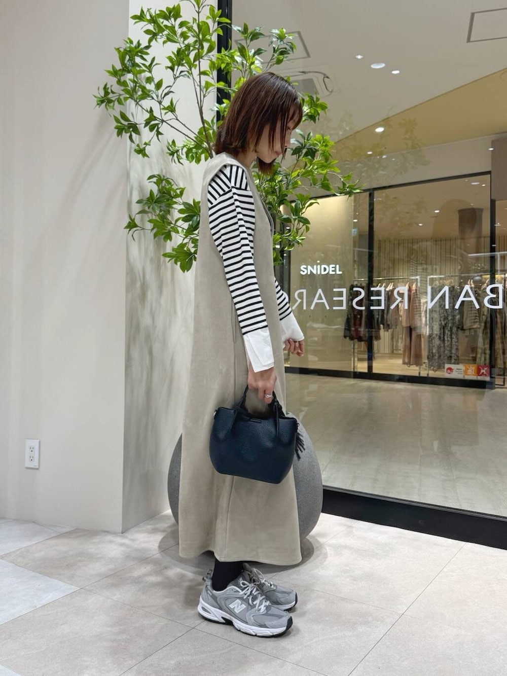 ブラック系のショルダーバッグ、ホワイト系のTシャツ/カットソー、グレー系のスニーカーを着用したレディースの冬コーディネートの2枚目の写真