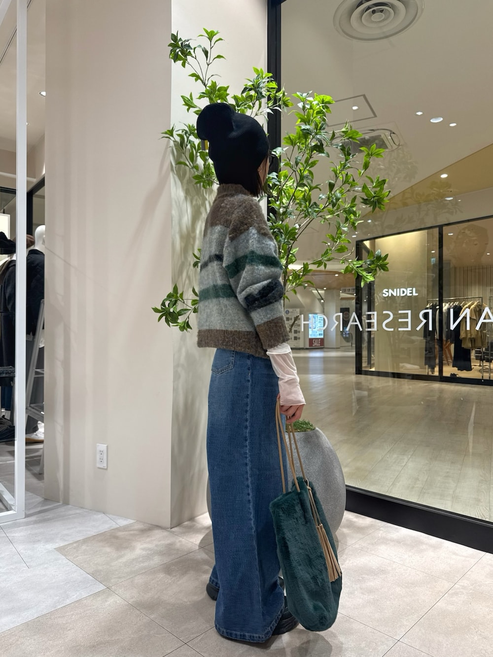 ブラウン系のニット/セーター、ホワイト系のTシャツ/カットソー、グリーン系のトートバッグを着用したレディースの秋コーディネートの2枚目の写真