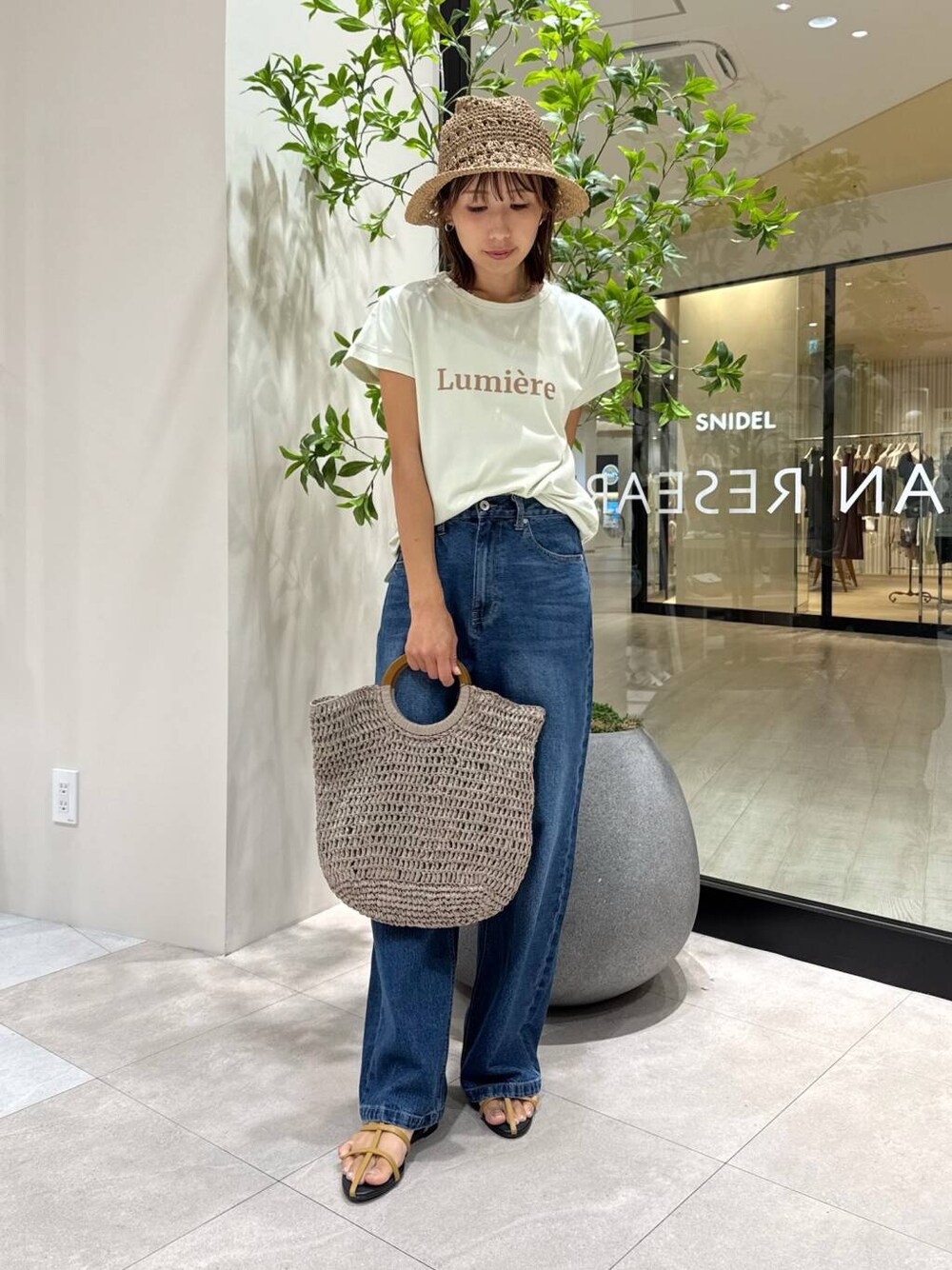 ブラウン系のサンダル、グレー系のトートバッグ、グリーン系のTシャツ/カットソーを着用したレディースの夏コーディネートの3枚目の写真