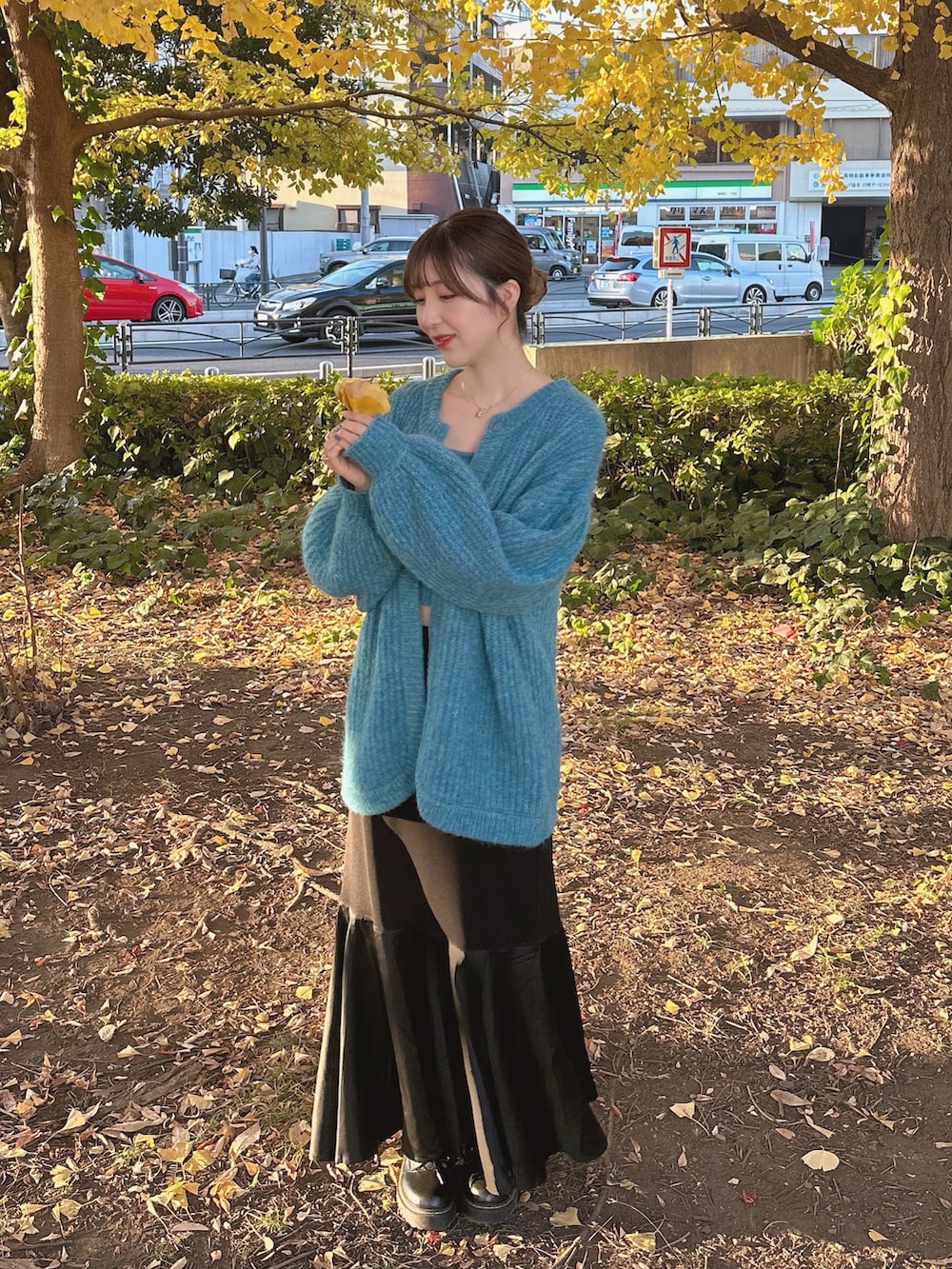 ブルー系のアンサンブル、ブラック系のスカート、ブラック系のブーツを着用したレディースの秋コーディネートの2枚目の写真