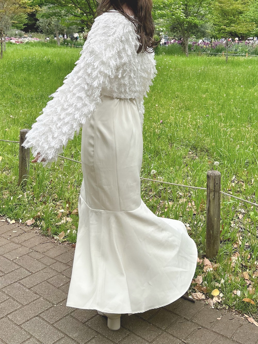 ホワイト系のカーディガン/ボレロ、ホワイト系のワンピース、ベージュ系のブーツを着用したレディースの春コーディネートの4枚目の写真