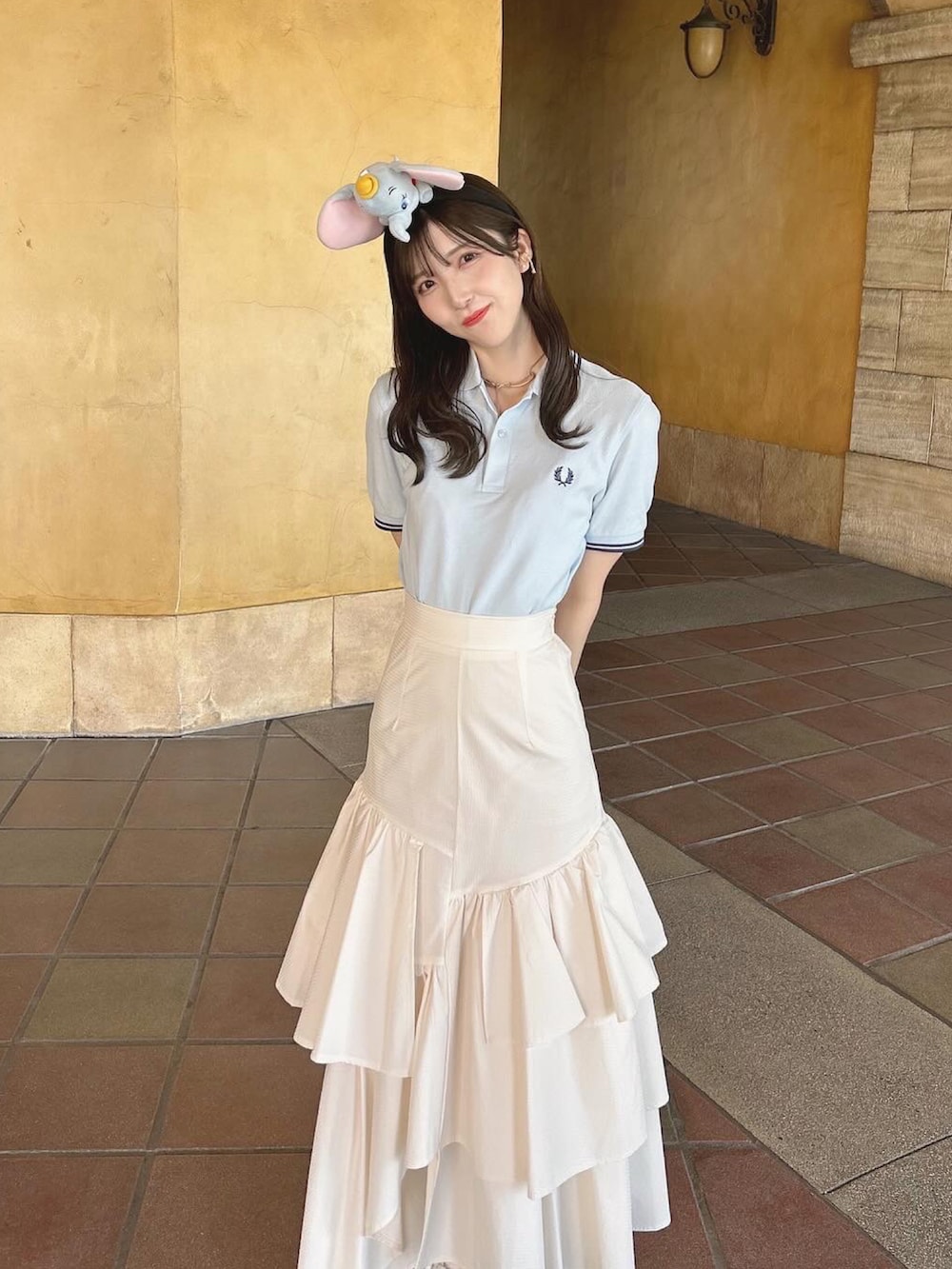 ブルー系のポロシャツ、ホワイト系のスカート、ホワイト系のスニーカーを着用したレディースの夏コーディネートの2枚目の写真