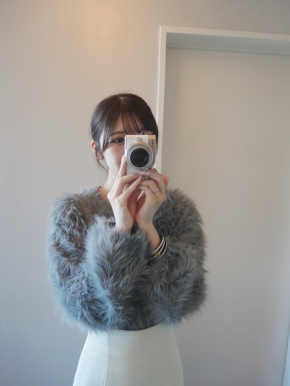 グレー系のカーディガン/ボレロ、ホワイト系のスカート、ブラウン系のショルダーバッグを着用したレディースの冬コーディネートの2枚目の写真