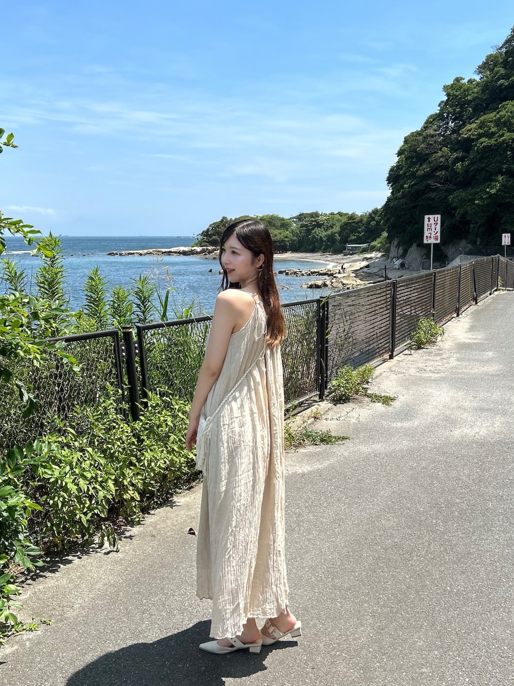 ベージュ系のバッグ、ベージュ系のワンピース/ドレス、ホワイト系のパンプスを着用したレディースの夏コーディネートの2枚目の写真