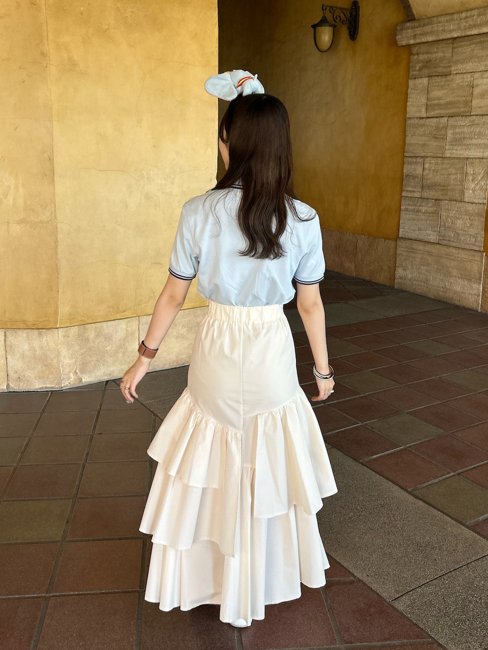 ブルー系のポロシャツ、ホワイト系のスカート、ホワイト系のスニーカーを着用したレディースの夏コーディネートの4枚目の写真
