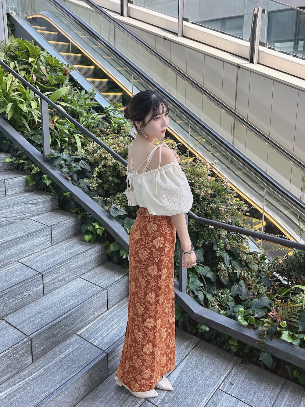 オレンジ系のスカート、ホワイト系のトップス、ホワイト系のキャミソールを着用したレディースの秋コーディネートの3枚目の写真