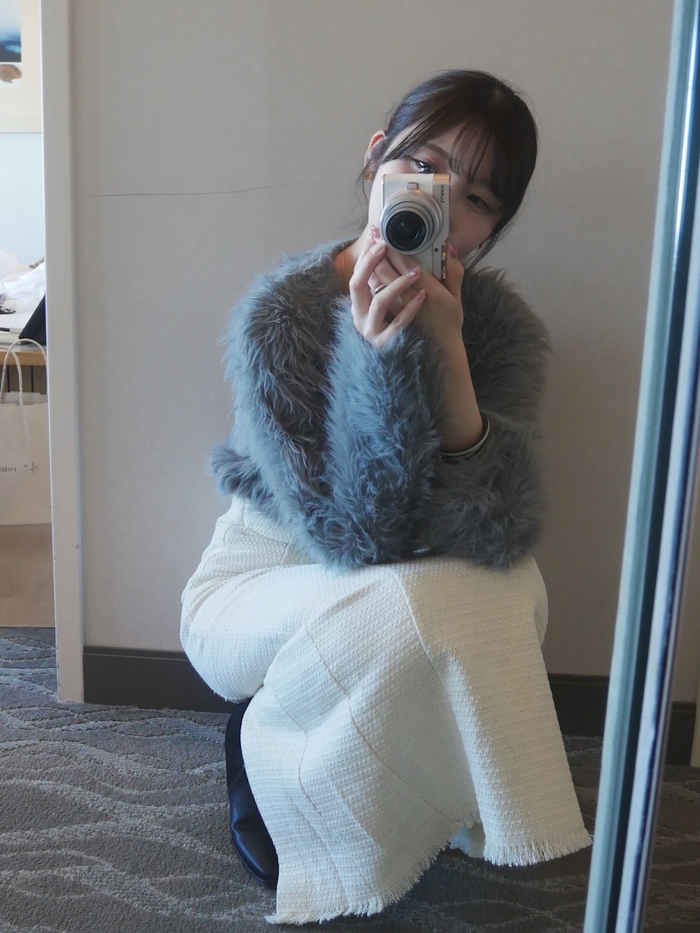 グレー系のカーディガン/ボレロ、ホワイト系のスカート、ブラウン系のショルダーバッグを着用したレディースの冬コーディネートの3枚目の写真