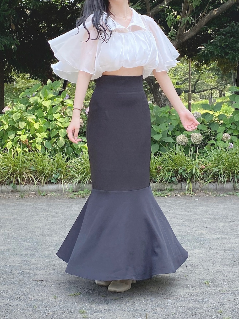 ブラック系のスカート、ホワイト系のその他トップス、ベージュ系のブーツを着用したレディースの夏コーディネートの5枚目の写真