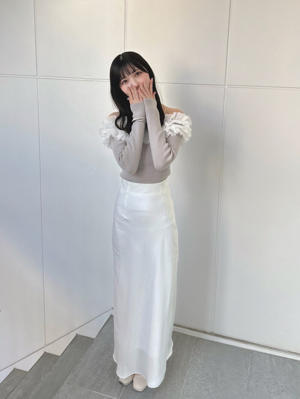 ホワイト系のスカート、ベージュ系のニット/セーターを着用したレディースの春コーディネートの2枚目の写真