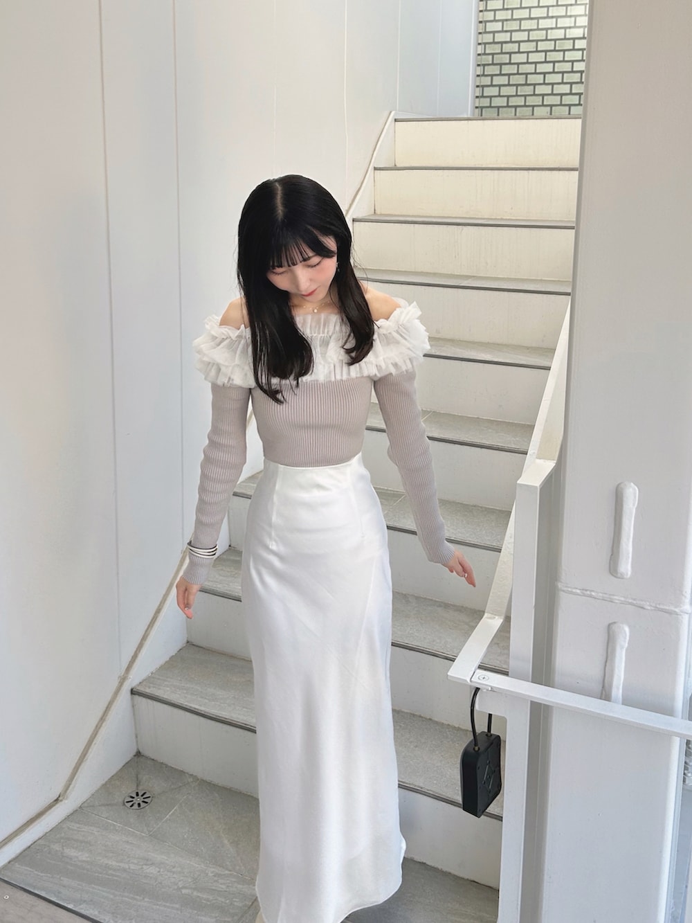 ホワイト系のスカート、ベージュ系のニット/セーターを着用したレディースの春コーディネートの3枚目の写真