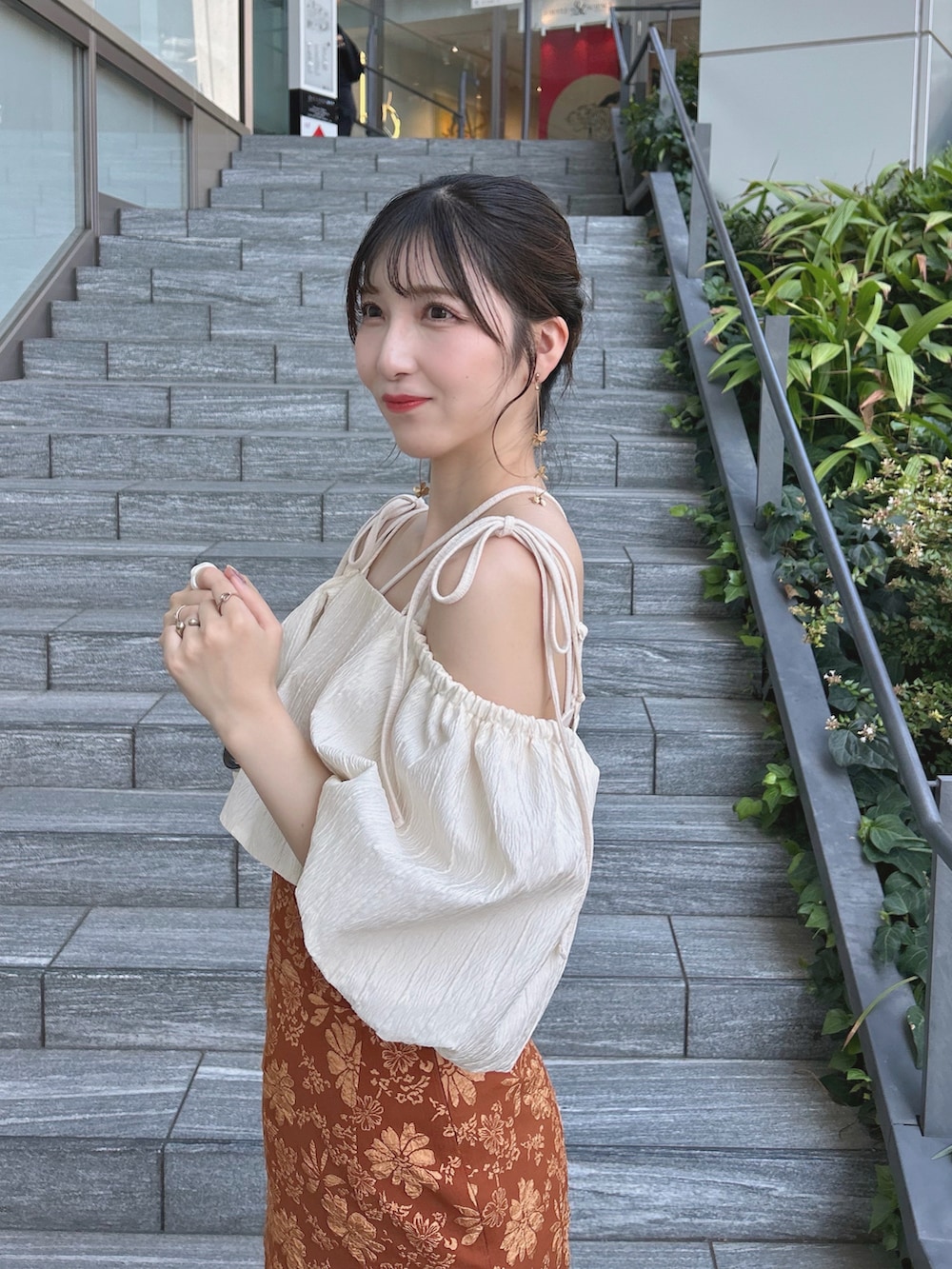 オレンジ系のスカート、ホワイト系のトップス、ホワイト系のキャミソールを着用したレディースの秋コーディネートの4枚目の写真