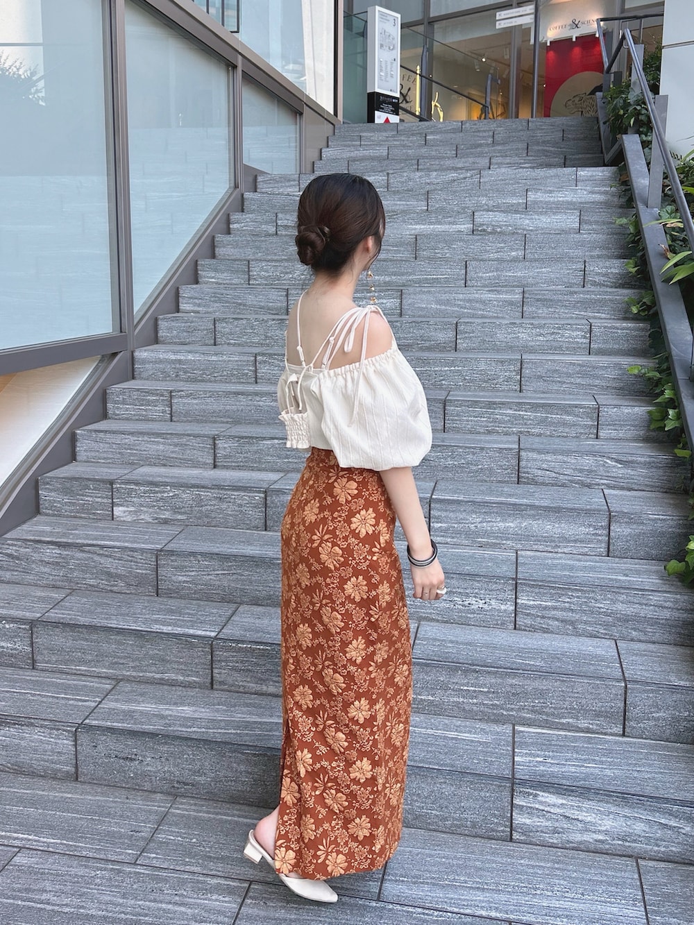 オレンジ系のスカート、ホワイト系のトップス、ホワイト系のキャミソールを着用したレディースの秋コーディネートの2枚目の写真