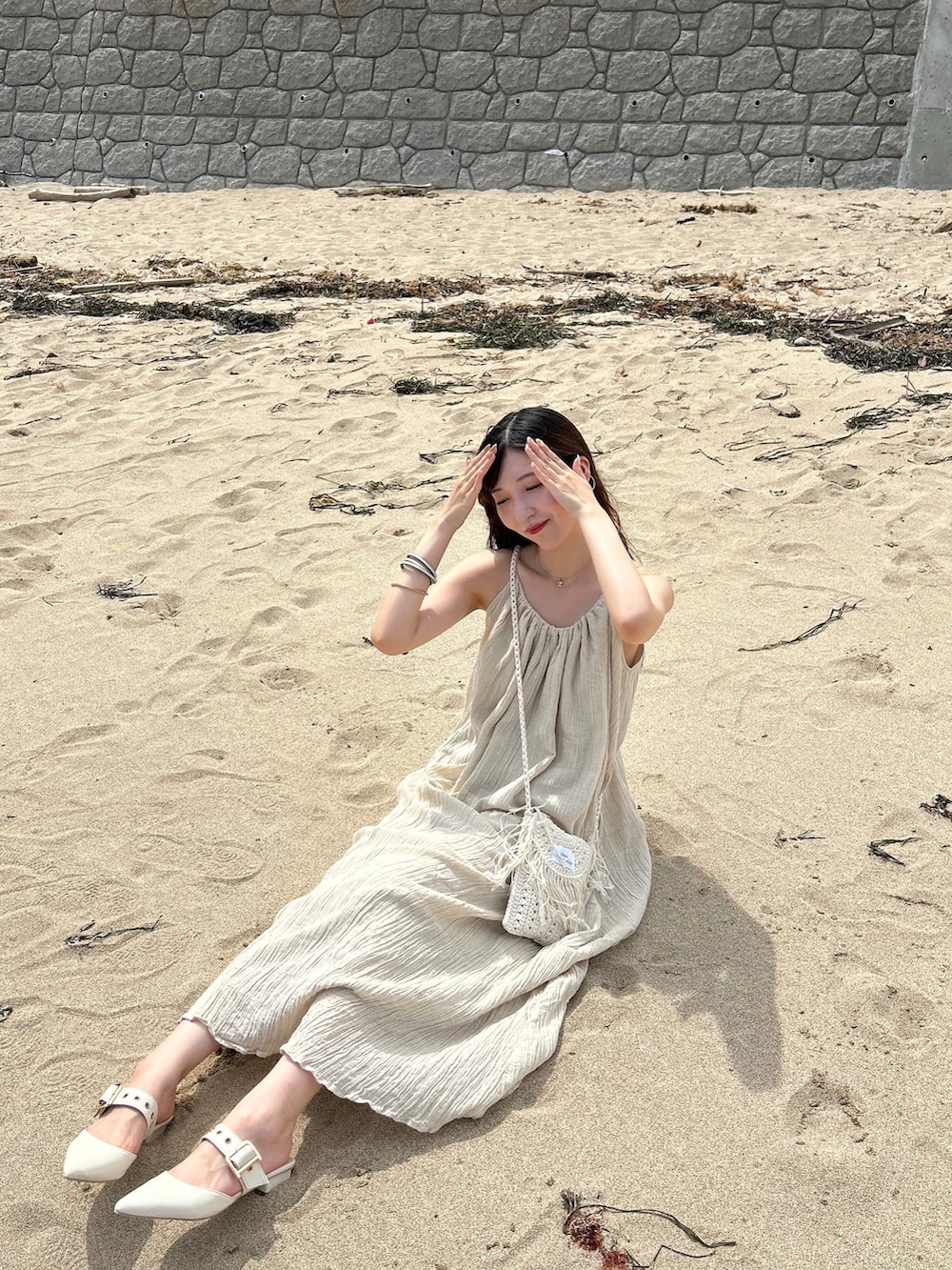 ベージュ系のバッグ、ベージュ系のワンピース/ドレス、ホワイト系のパンプスを着用したレディースの夏コーディネートの4枚目の写真