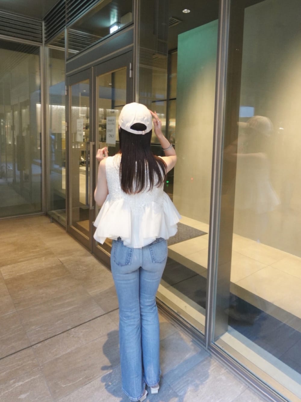 ホワイト系のパンプス、ホワイト系のシャツ/ブラウス、ブルー系のデニムパンツを着用したレディースの夏コーディネートの2枚目の写真