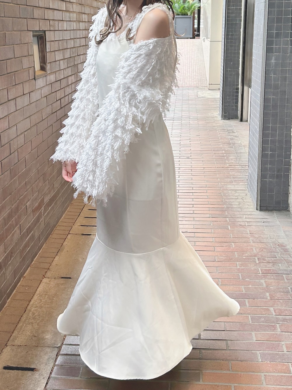 ホワイト系のカーディガン/ボレロ、ホワイト系のワンピース、ベージュ系のブーツを着用したレディースの春コーディネートの3枚目の写真