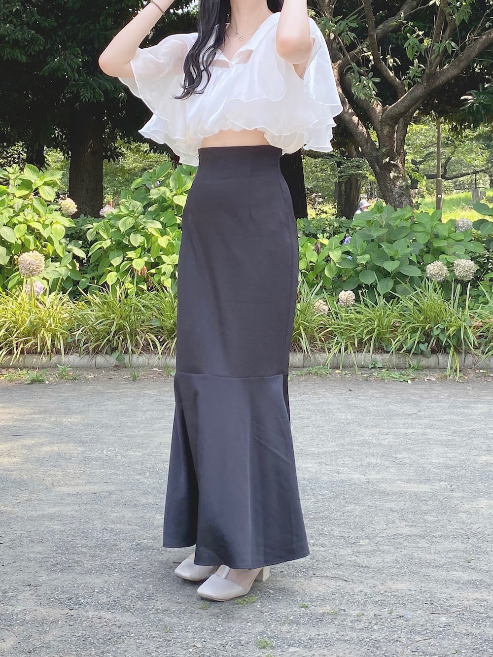 ブラック系のスカート、ホワイト系のその他トップス、ベージュ系のブーツを着用したレディースの夏コーディネートの3枚目の写真