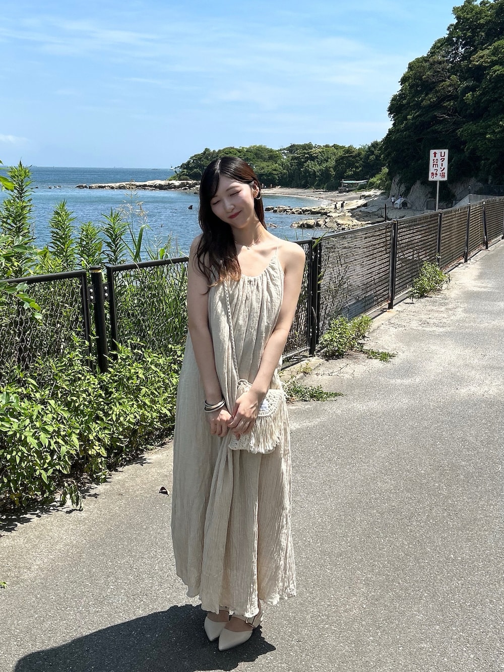 ベージュ系のバッグ、ベージュ系のワンピース/ドレス、ホワイト系のパンプスを着用したレディースの夏コーディネートの3枚目の写真