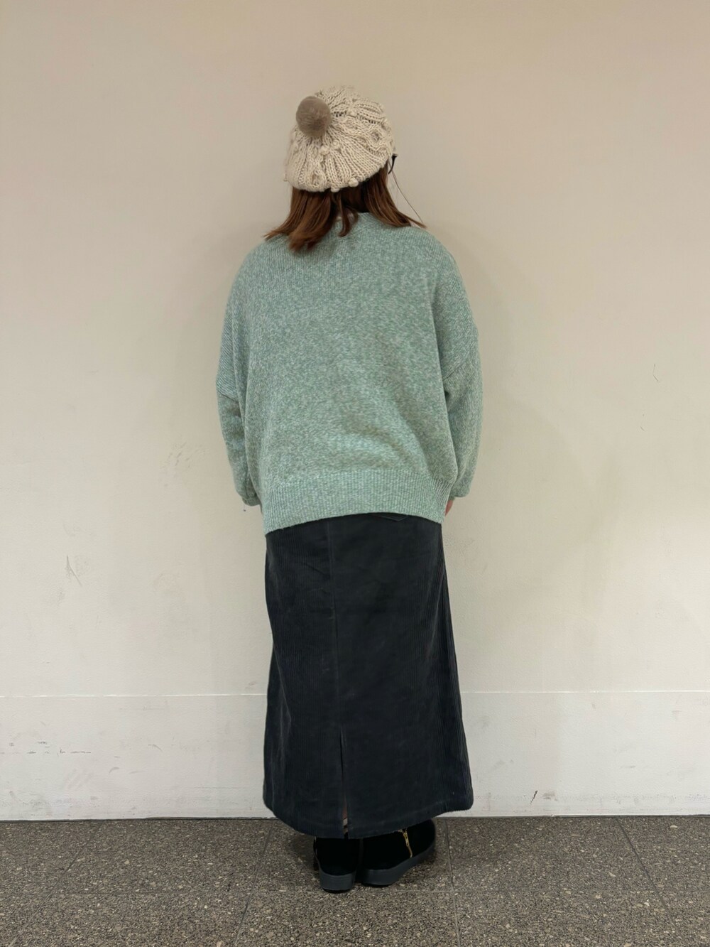 グリーン系のカーディガン/ボレロ、ブルー系のスカート、ホワイト系のハットを着用したレディースの冬コーディネートの3枚目の写真