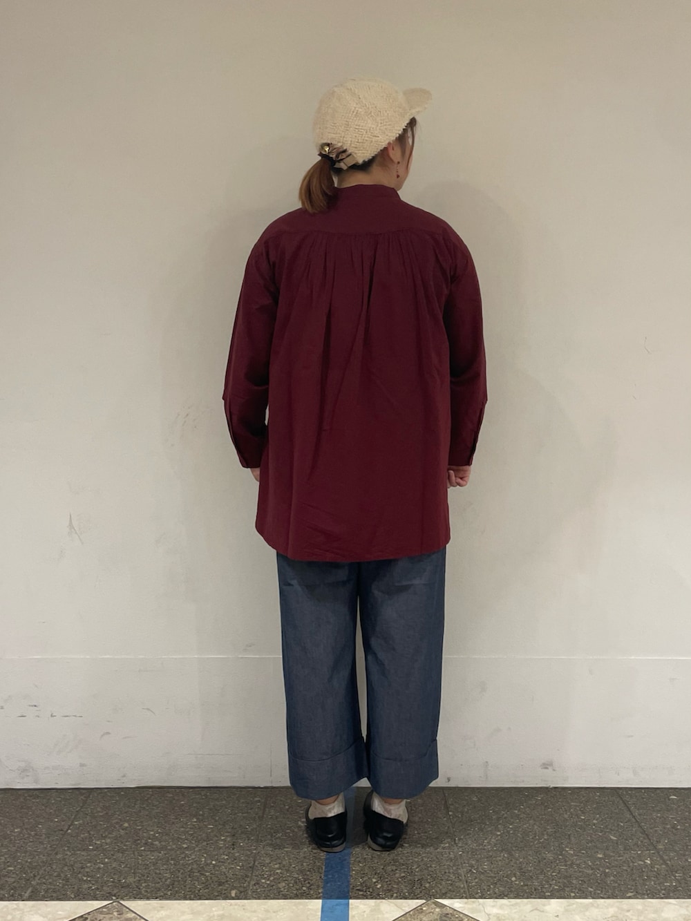 レッド系のチュニック、ブルー系のデニムパンツ、ホワイト系のハットを着用したレディースの秋コーディネートの2枚目の写真