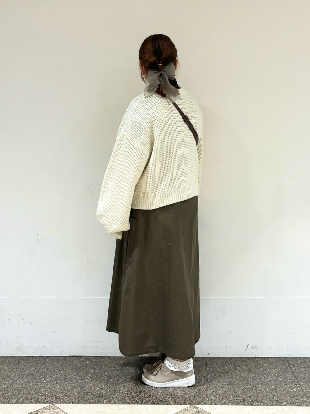 グリーン系のワンピース、ブラウン系のハンドバッグを着用したレディースの冬コーディネートの2枚目の写真