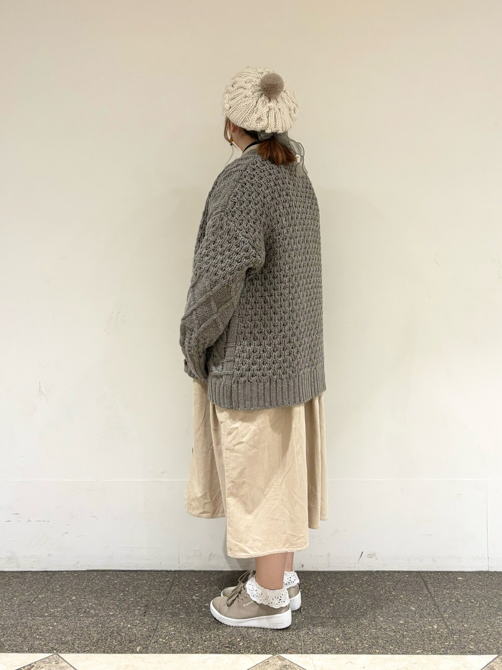 ブラウン系のカーディガン/ボレロ、ベージュ系のワンピース、ホワイト系のハットを着用したレディースの冬コーディネートの2枚目の写真