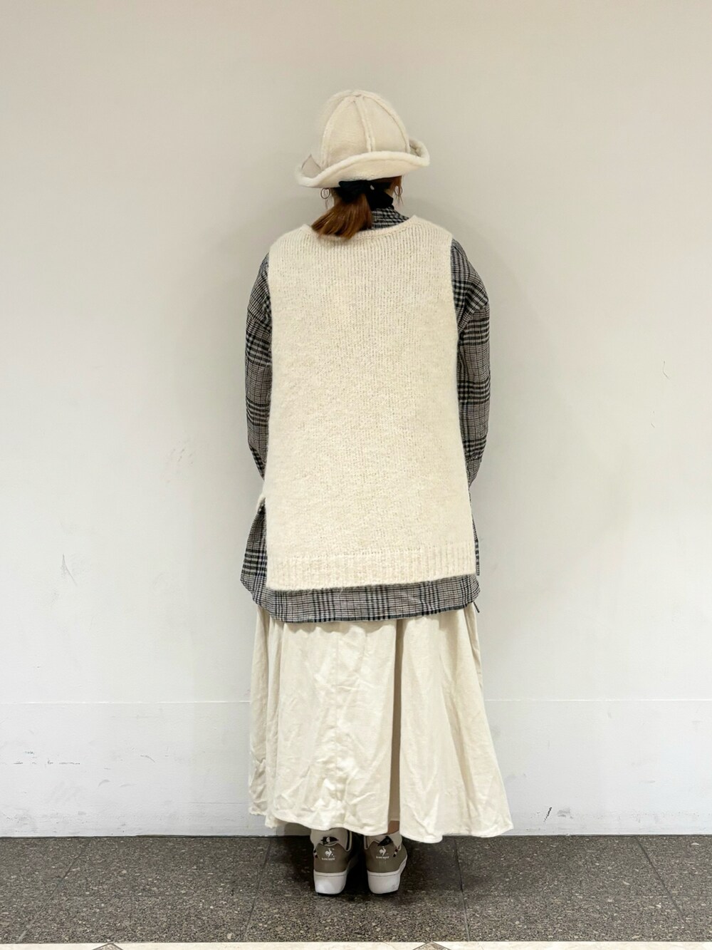 ホワイト系のベスト、ホワイト系のチュニック、ベージュ系のスカートを着用したレディースの冬コーディネートの3枚目の写真