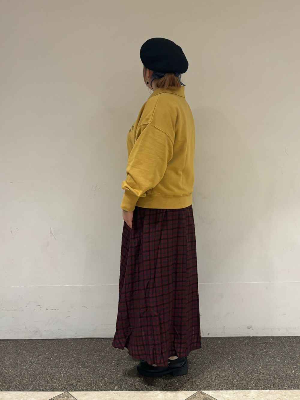 イエロー系のTシャツ/カットソー、レッド系のスカート、ブラック系のハットを着用したレディースの秋コーディネートの2枚目の写真