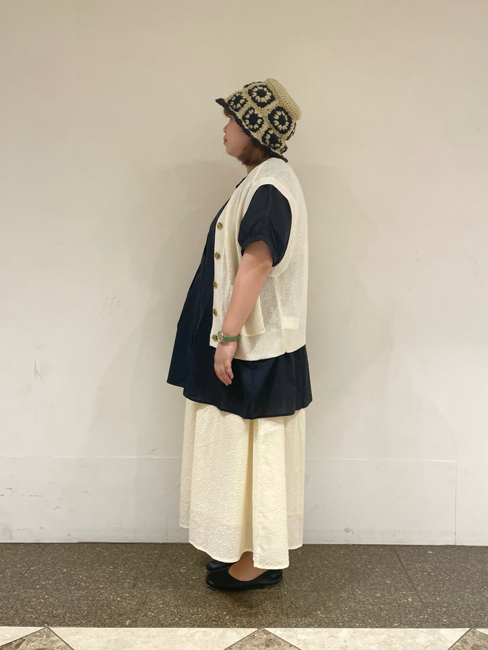 ブラック系のチュニック、ホワイト系のベスト、ホワイト系のスカートを着用したレディースの秋コーディネートの2枚目の写真