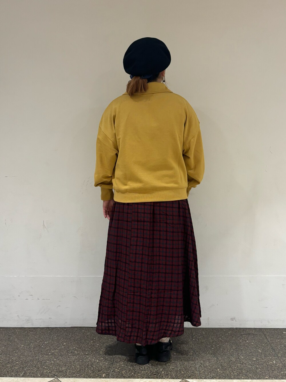 イエロー系のTシャツ/カットソー、レッド系のスカート、ブラック系のハットを着用したレディースの秋コーディネートの3枚目の写真