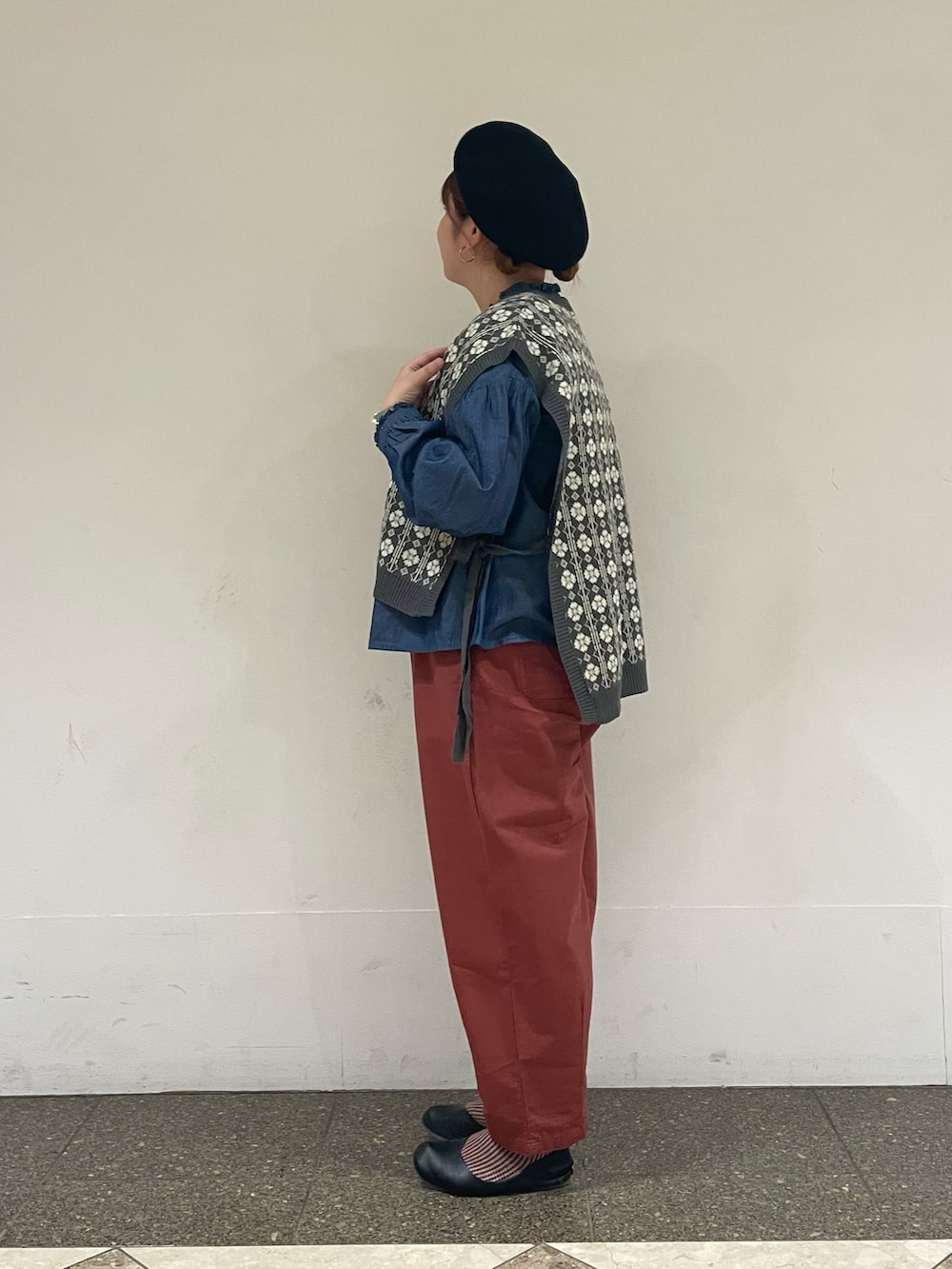 グレー系のベスト、ブルー系のシャツ/ブラウス、ブラウン系のその他パンツを着用したレディースの秋コーディネートの2枚目の写真