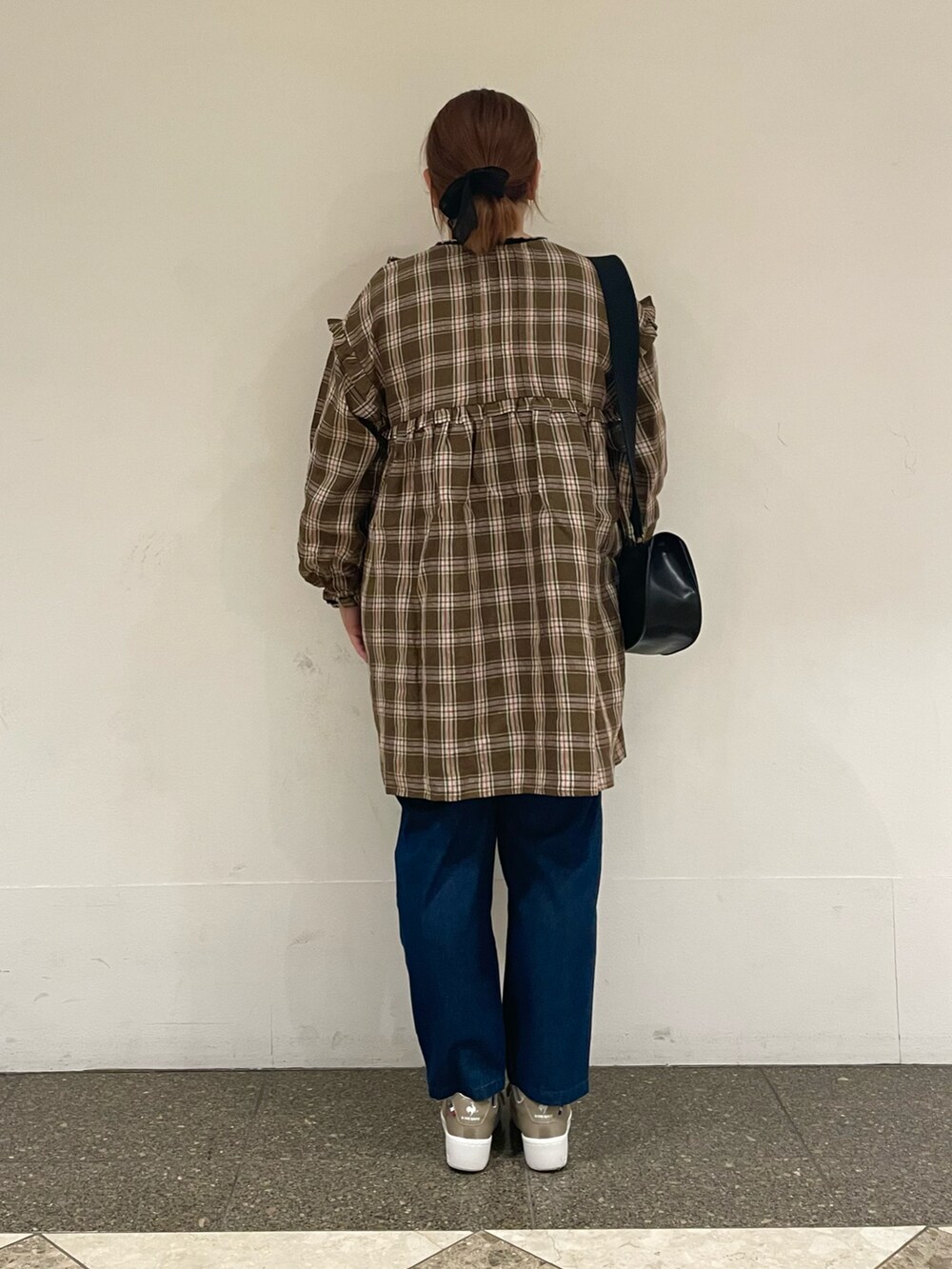 グリーン系のチュニック、ブルー系のデニムパンツ、ブラック系のハンドバッグを着用したレディースの秋コーディネートの3枚目の写真