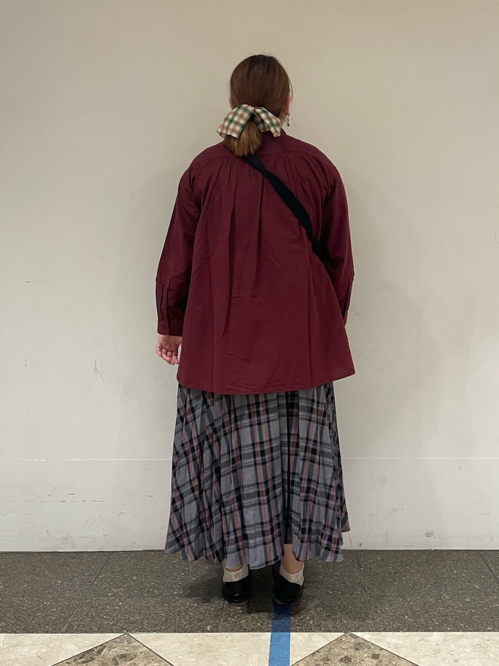 レッド系のチュニック、グレー系のスカート、ブラック系のハンドバッグを着用したレディースの秋コーディネートの3枚目の写真