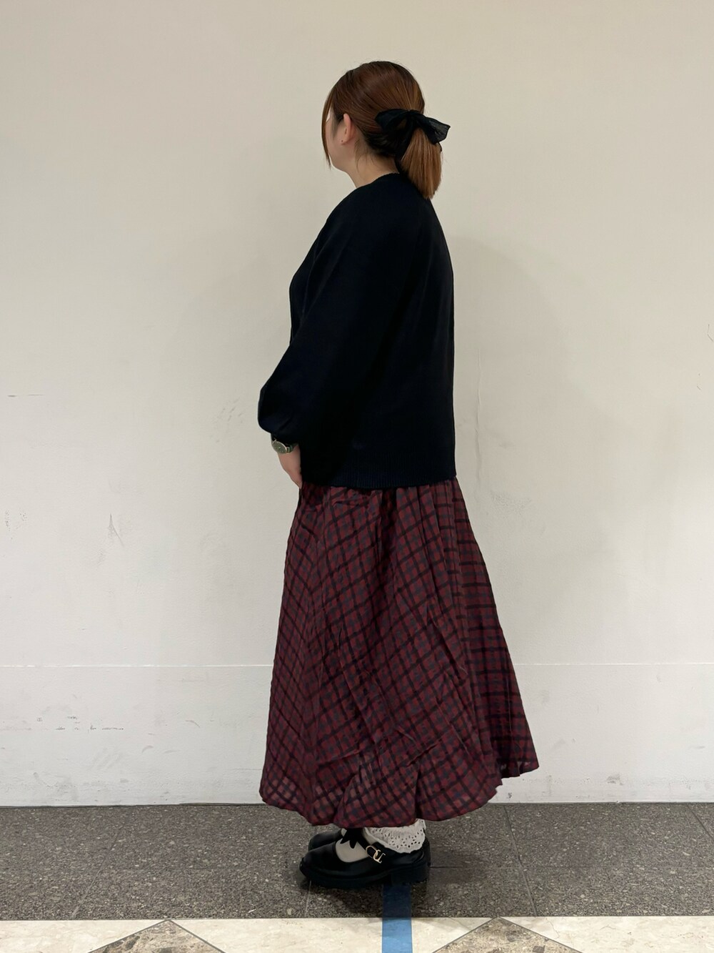 ブラック系のカーディガン/ボレロ、レッド系のスカート、ブラック系のハンドバッグを着用したレディースの秋コーディネートの2枚目の写真