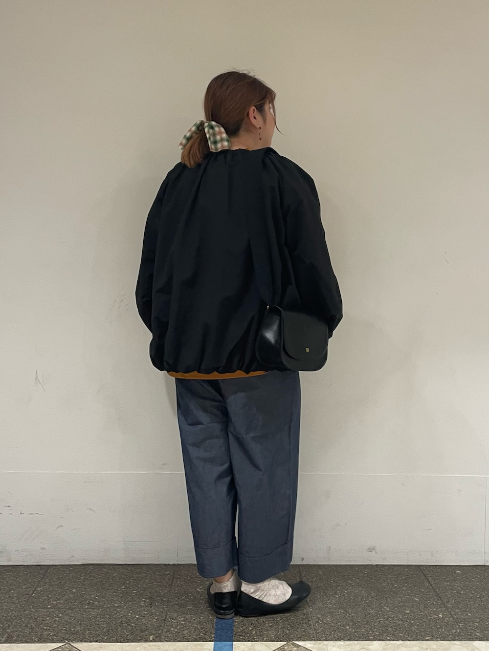 イエロー系のTシャツ/カットソー、ブラック系のブルゾン、ブルー系のデニムパンツを着用したレディースの秋コーディネートの3枚目の写真